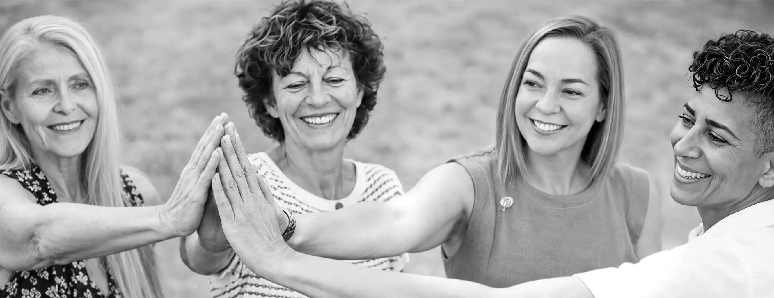 Four women joining hands in solidarity